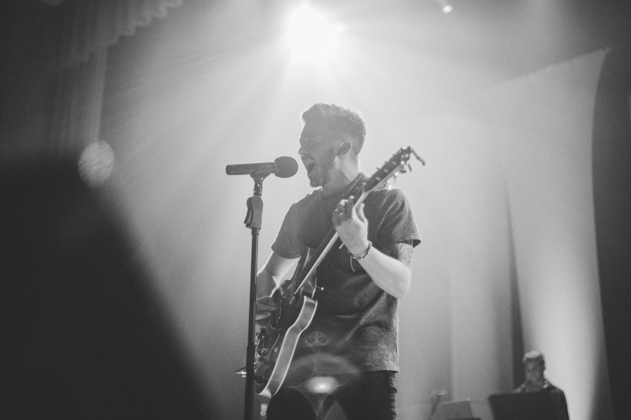 Man Playing Guitar Singing into a Mic